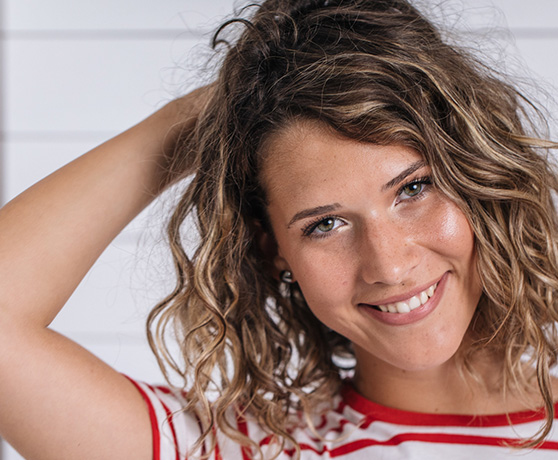 Smiling Woman Wearing a Striped Top with Curly Hair Balayage