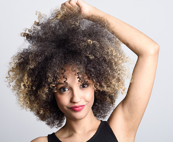 Young Woman Holding her Super Curly Hair with Ombre